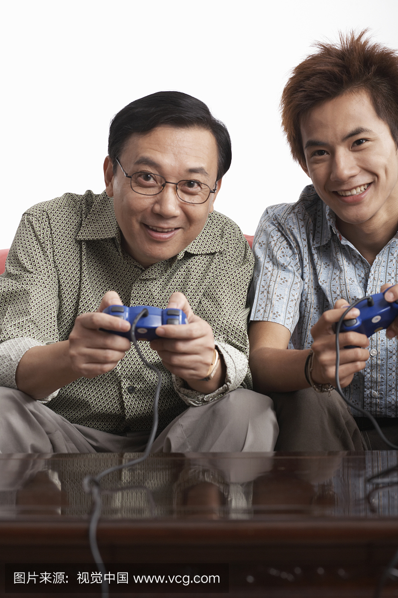 父亲和少年儿子玩视频游戏,在室内