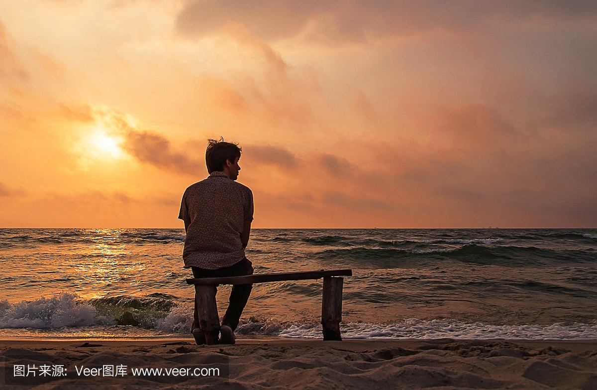 寂寞的男人坐在海边的长凳上