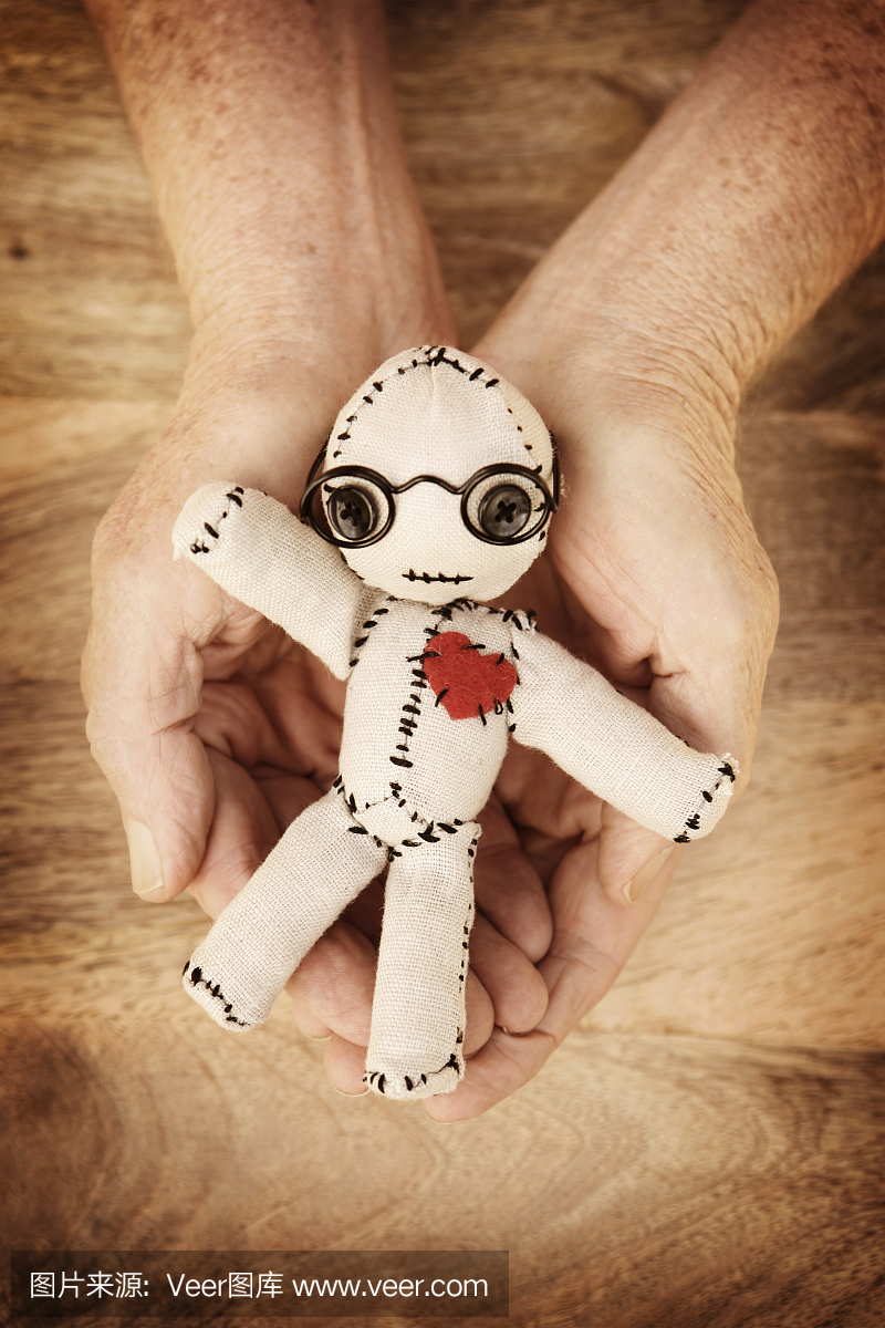 巫术娃娃在成熟的手在木背景