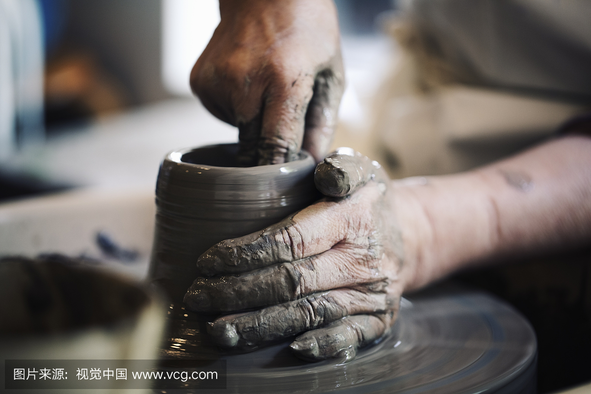 制作陶瓷的高级女人的手与陶工的车轮工作