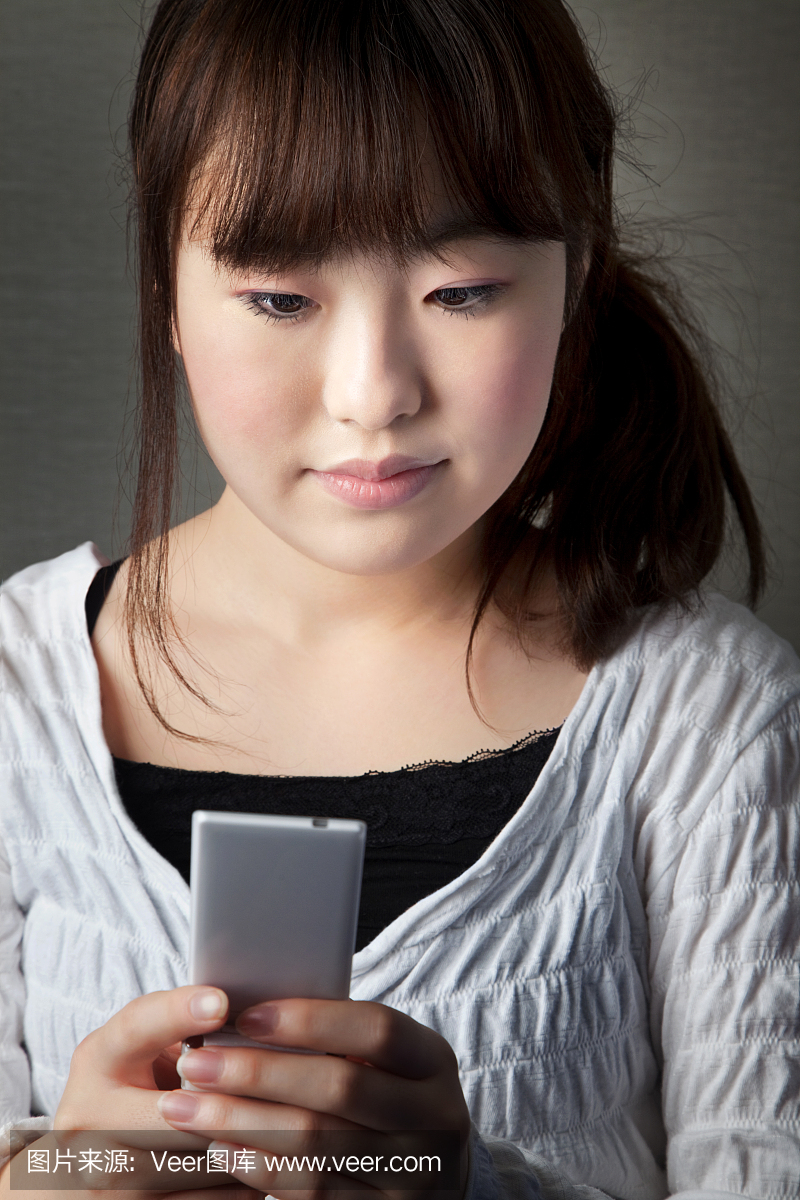 年轻的日本女孩在手机上发短信