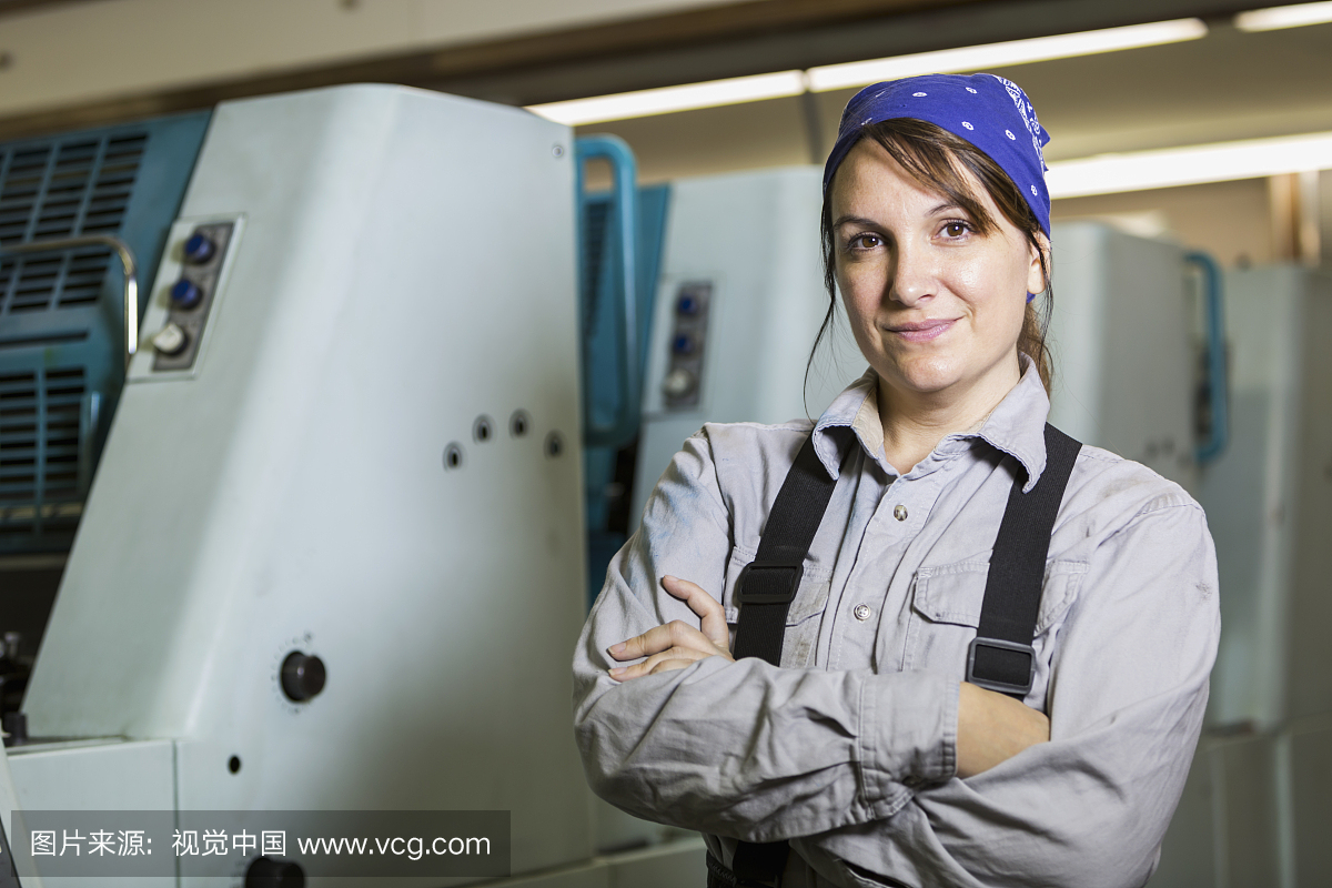在印刷厂工作的女人由印刷机站立