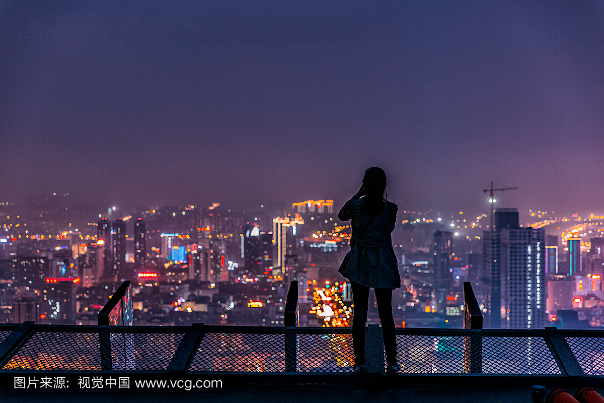 站在屋顶俯瞰城市夜景的人