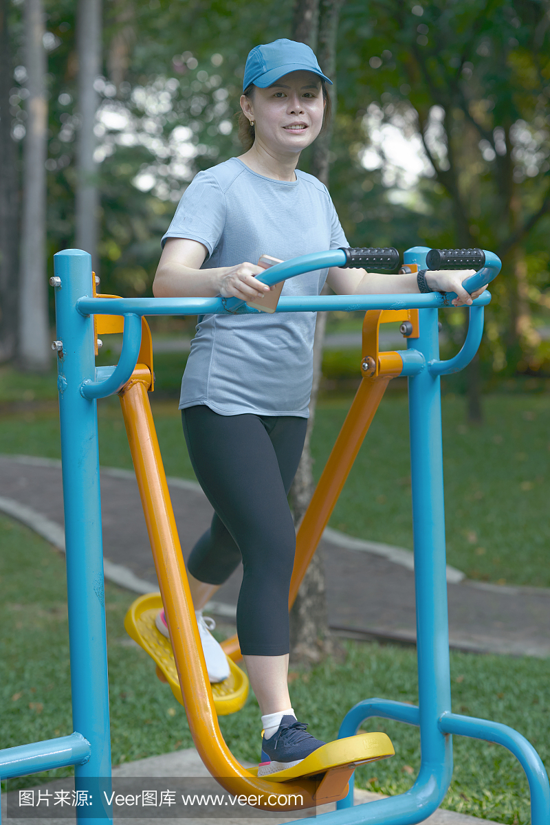 微笑对公园里的椭圆步行教练健身机锻炼的女人