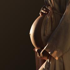 美丽一名孕妇的侧面影像与腹部的亮点