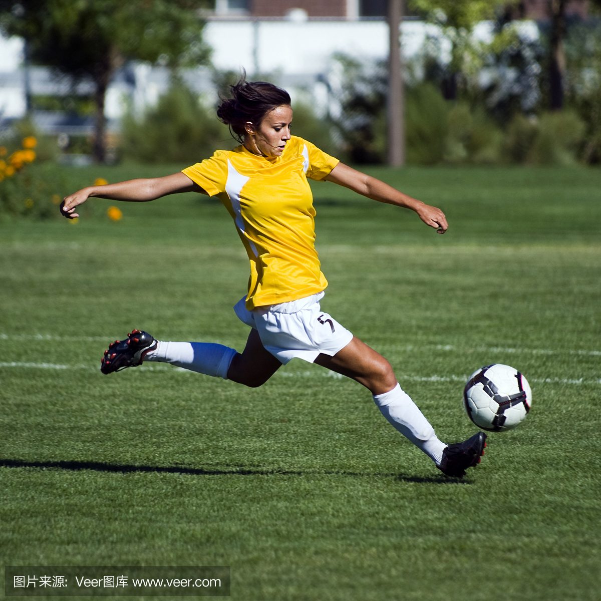 黄色的女子足球运动员跳跃触摸弹跳球