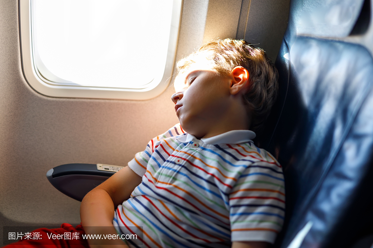 睡觉在飞机上的长途飞行期间的小孩男孩。孩子