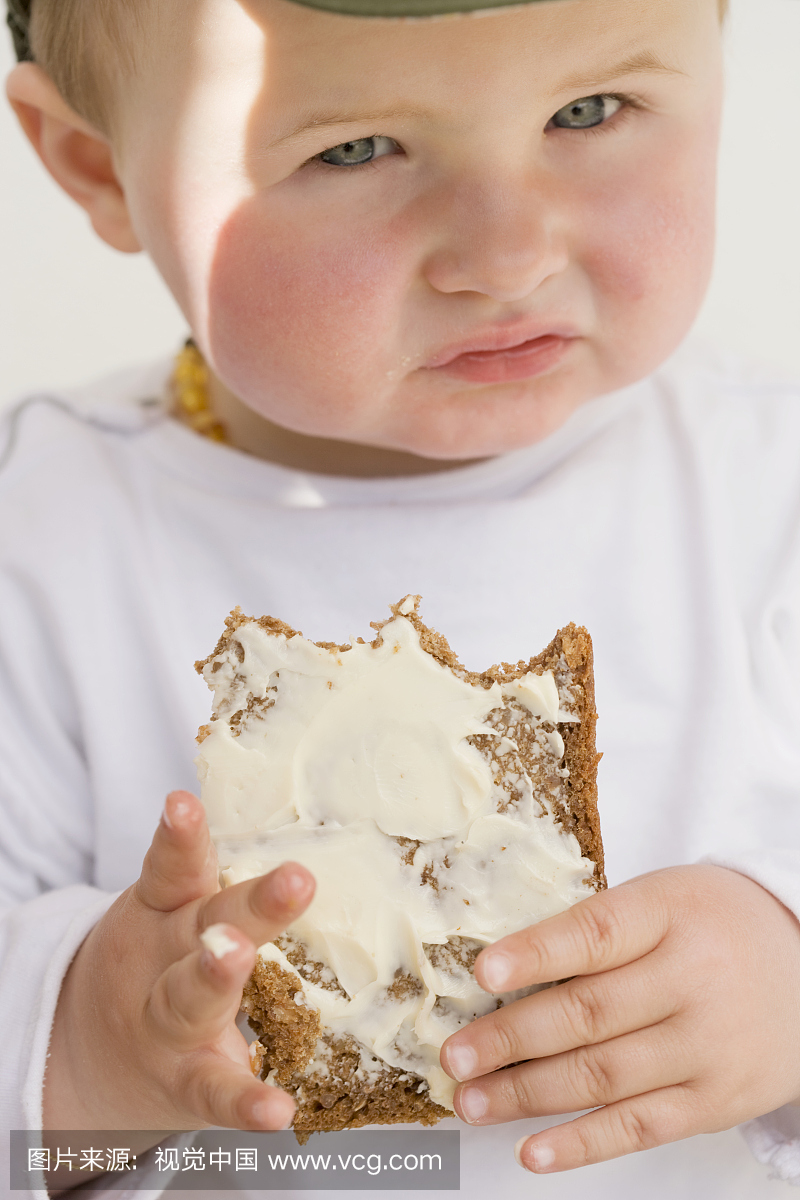 婴儿(12-23个月)拿着面包和黄油片,特写镜头