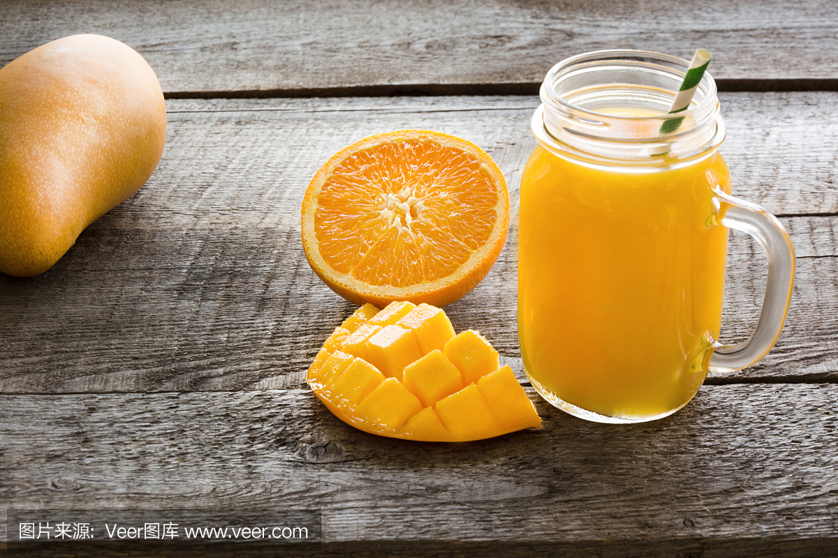 热带果汁芒果,橙子,香蕉水果在罐中与秸秆在木