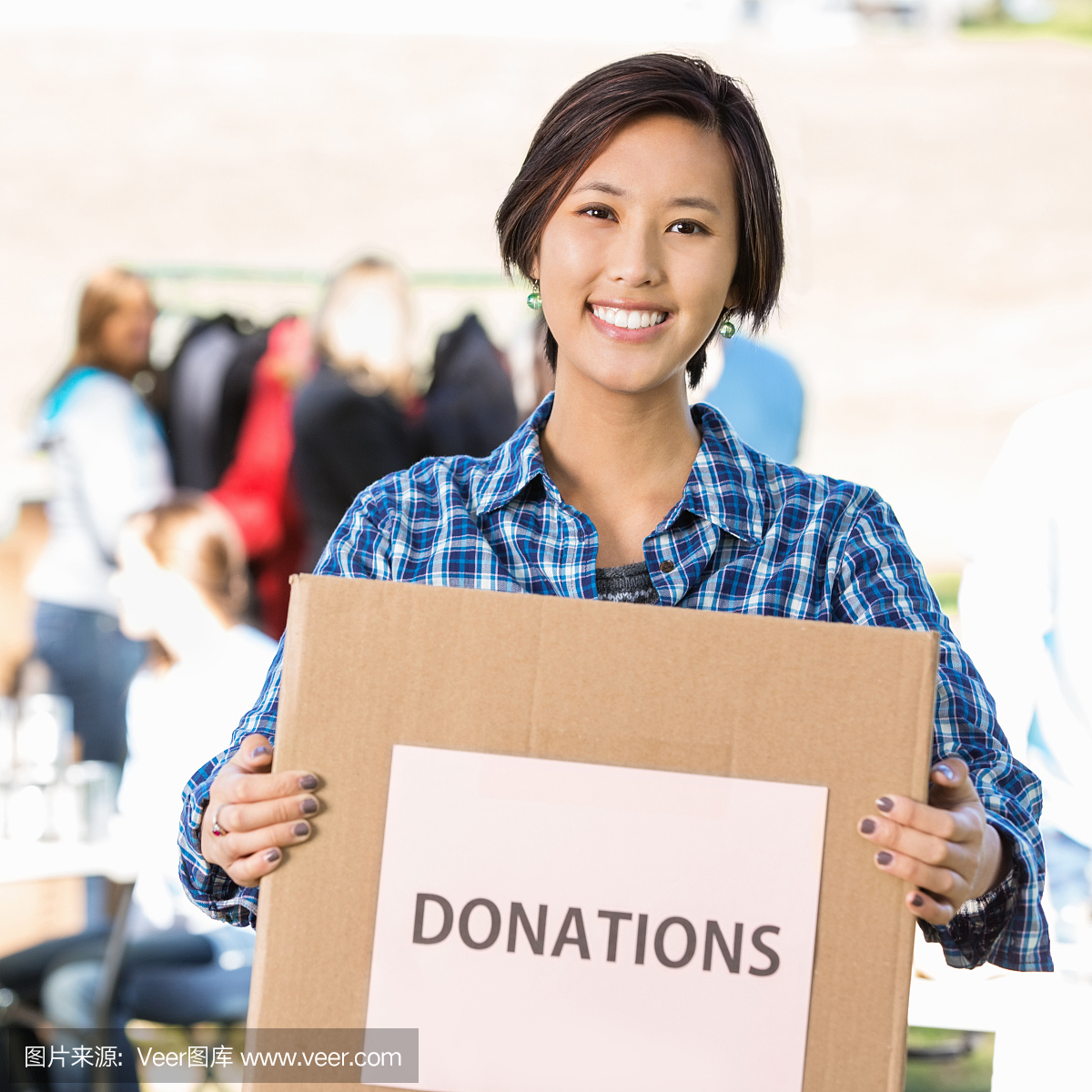 亚洲女志愿者在慈善机构举行捐款箱