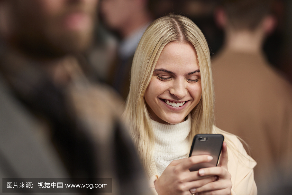 手机微笑在人群中的发短信的女人