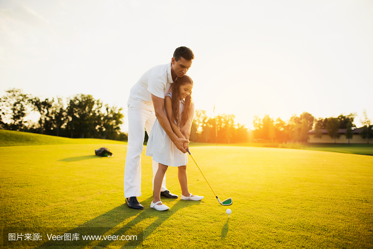 一个男人正在教一个准备让她第一次打高尔夫球