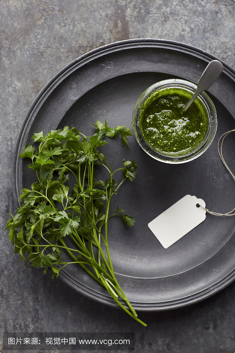 Parsley pesto in a jar on pewter plate