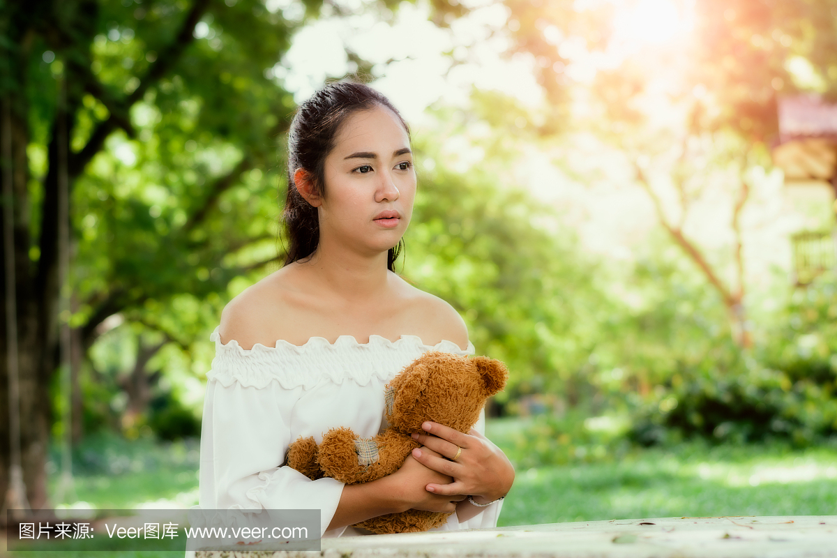 孤独的女孩在公园里,悲伤的女孩与玩具熊。