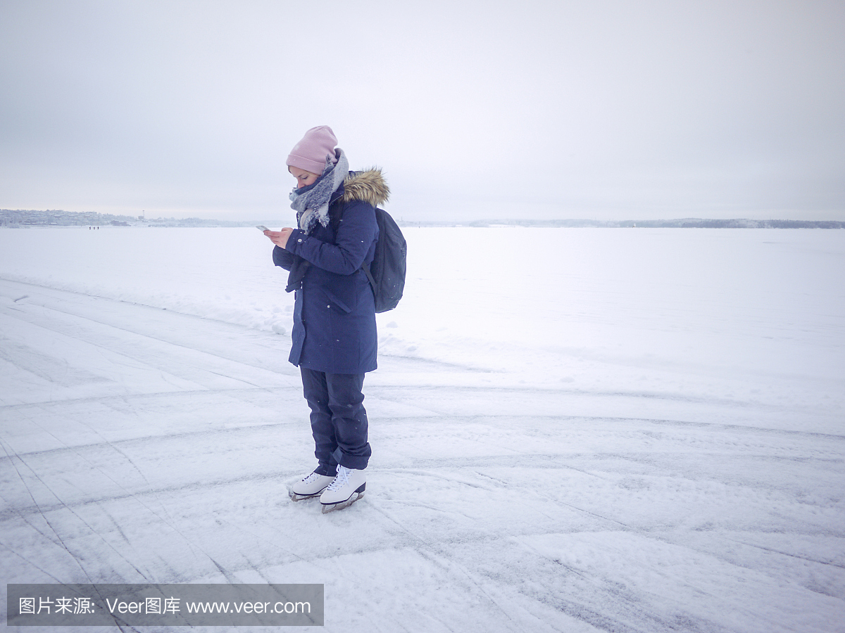 芬兰生活方式,年轻女子检查她的手机,同时在冰