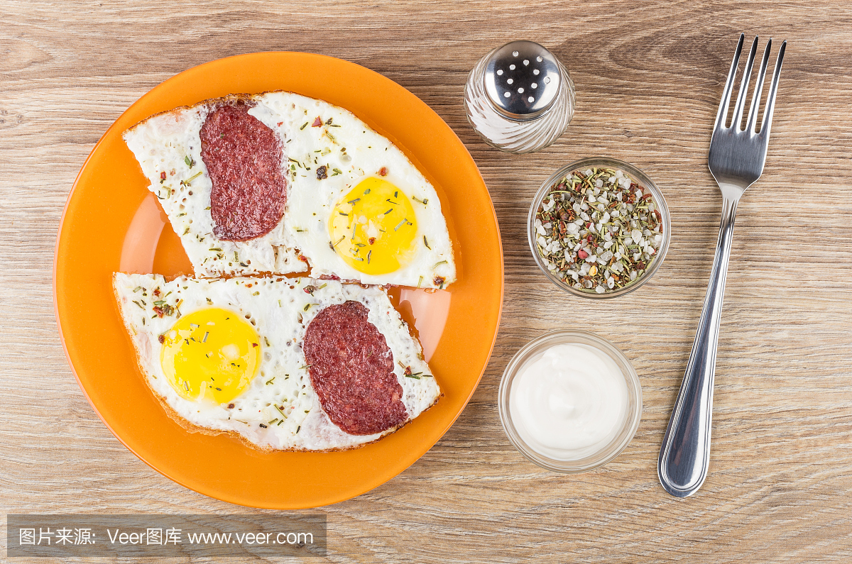 煎鸡蛋用香肠在橙色盘子,盐,香料,蛋黄酱