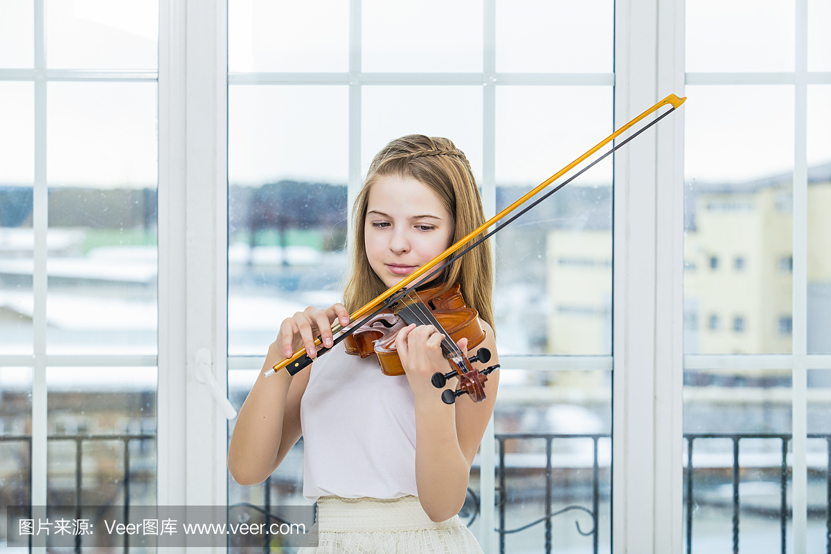 儿童女孩拉小提琴学习美丽和快乐在一个白色的