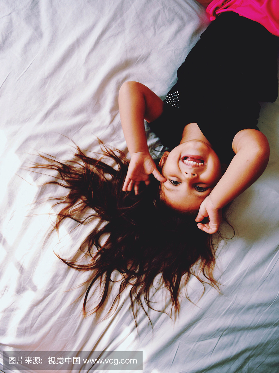 躺在床上和微笑在床上的女孩的高角度视图