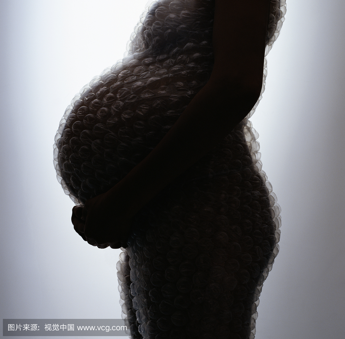 怀孕的女人裹着泡沫包裹手牵着手在胃下