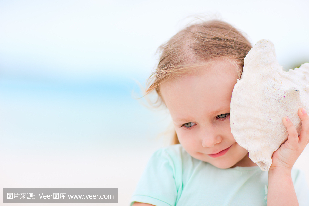 一个小女孩在沙发上抱着一个海壳到她的耳朵