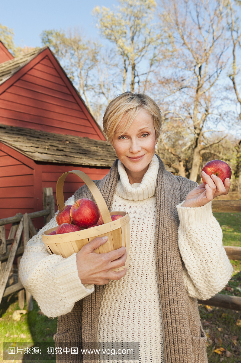美国,新泽西州,肖像的微笑的女人拿着篮子与苹