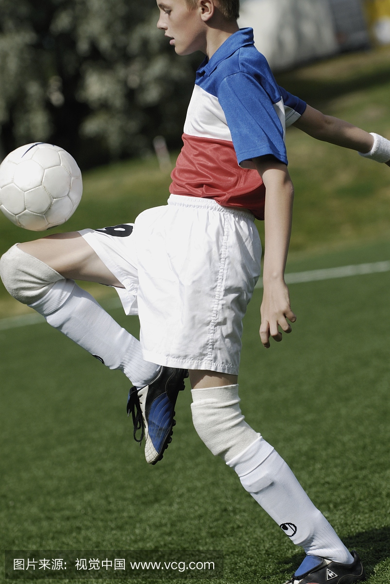 在大腿上平衡足球的足球运动员的侧面轮廓