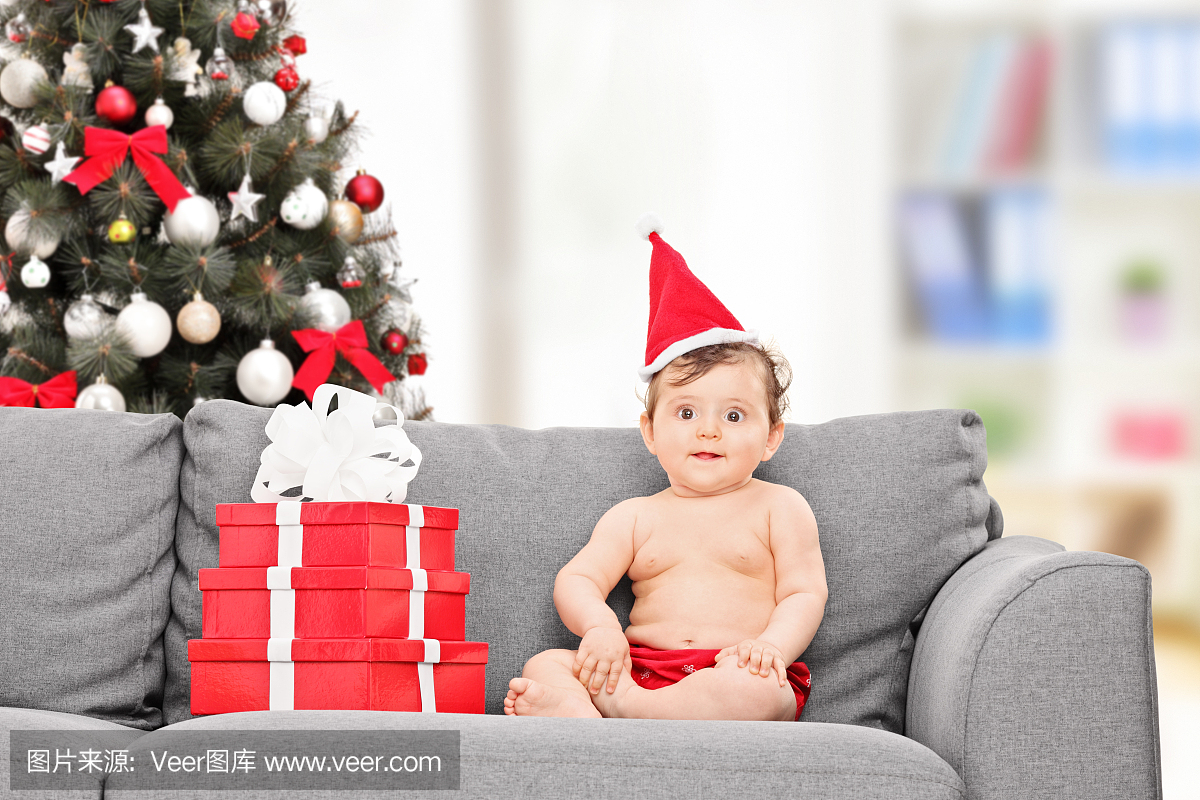 圣诞老人帽子坐在沙发上的小宝宝