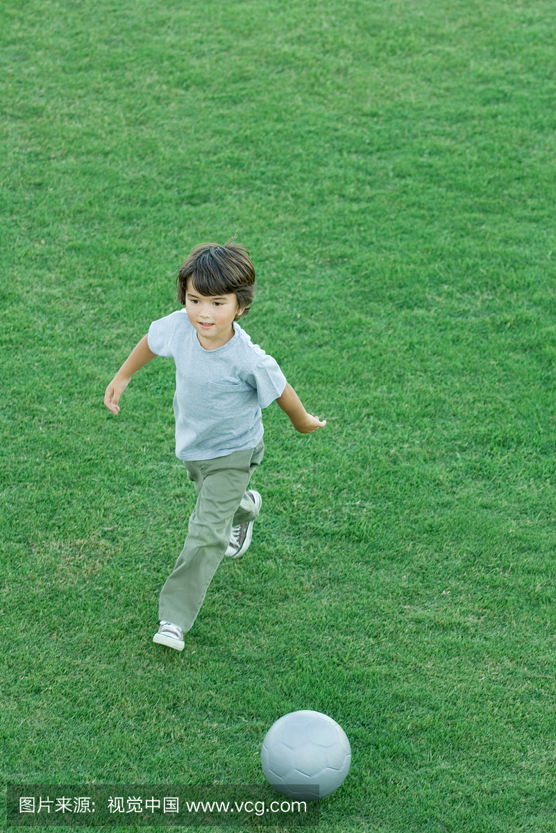 男孩在草地上踢足球,高角度视图,全长
