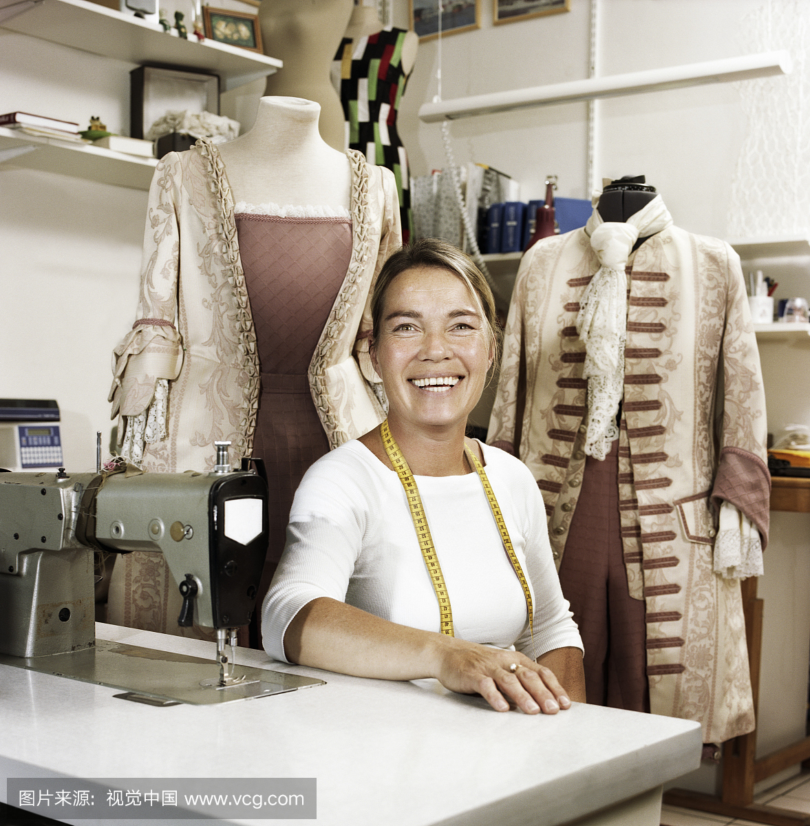 女裁缝机坐在缝纫机,微笑,肖像