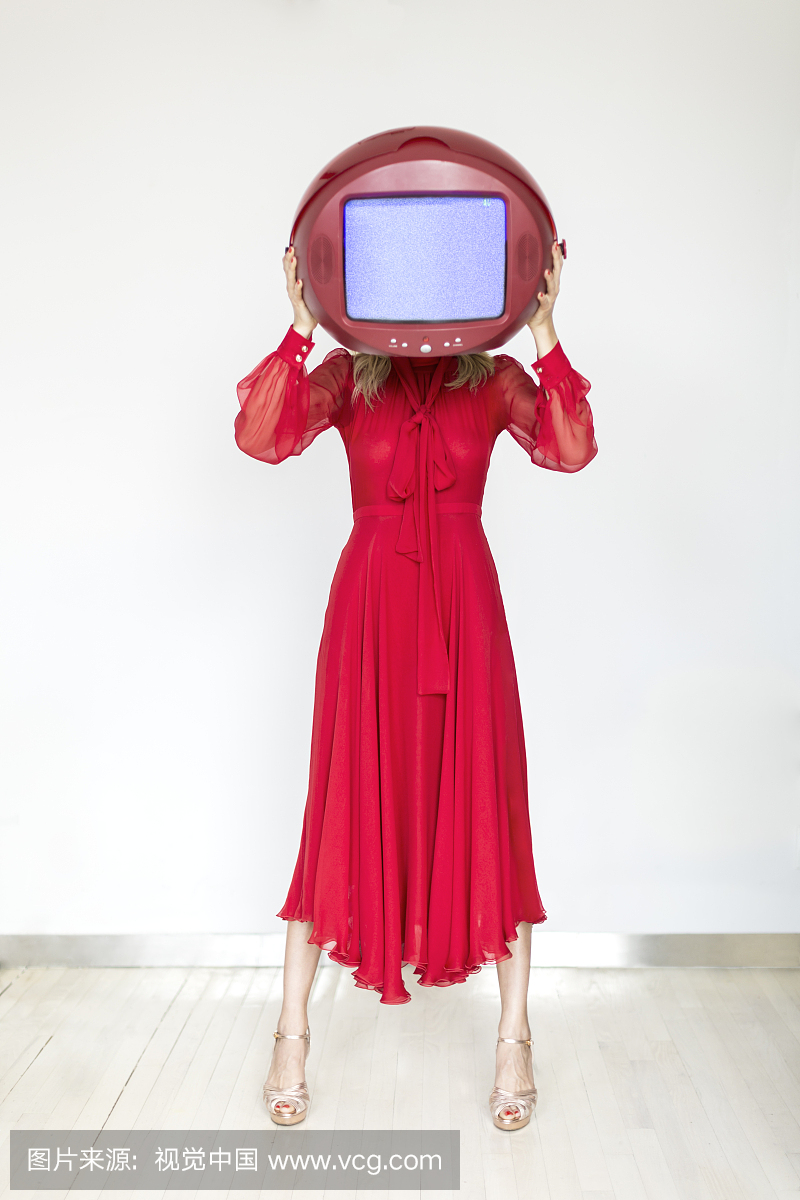 红丝绸连衣裙的妇女在她面前拿着电视