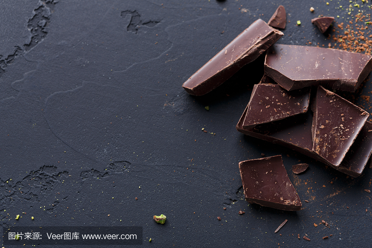 碎的巧克力碎片和可可粉在黑色背景上