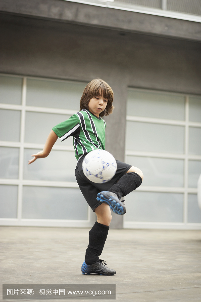 男孩(8-10)在车道练习足球
