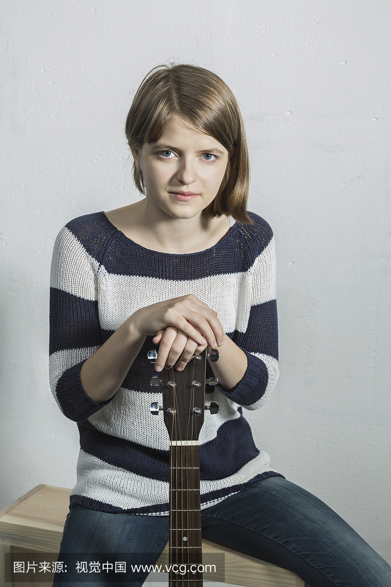 Portrait of smiling teenager holding guitar while