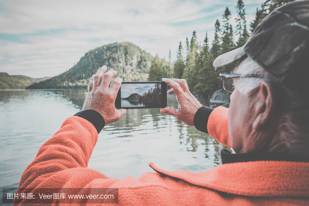 老人用智能手机拍摄湖自然的图片