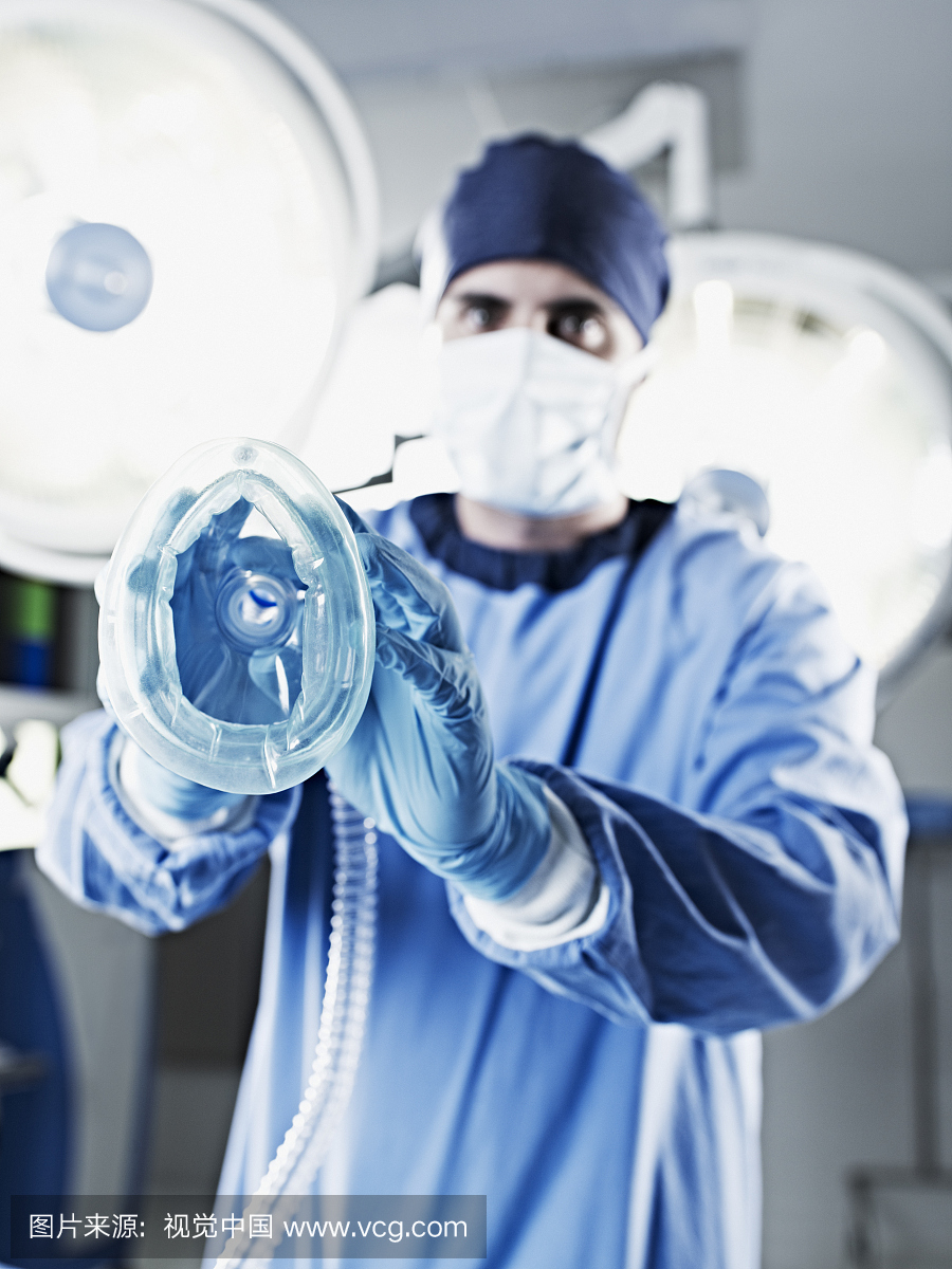 外科医生在外科手术灯下手持氧气面罩的肖像