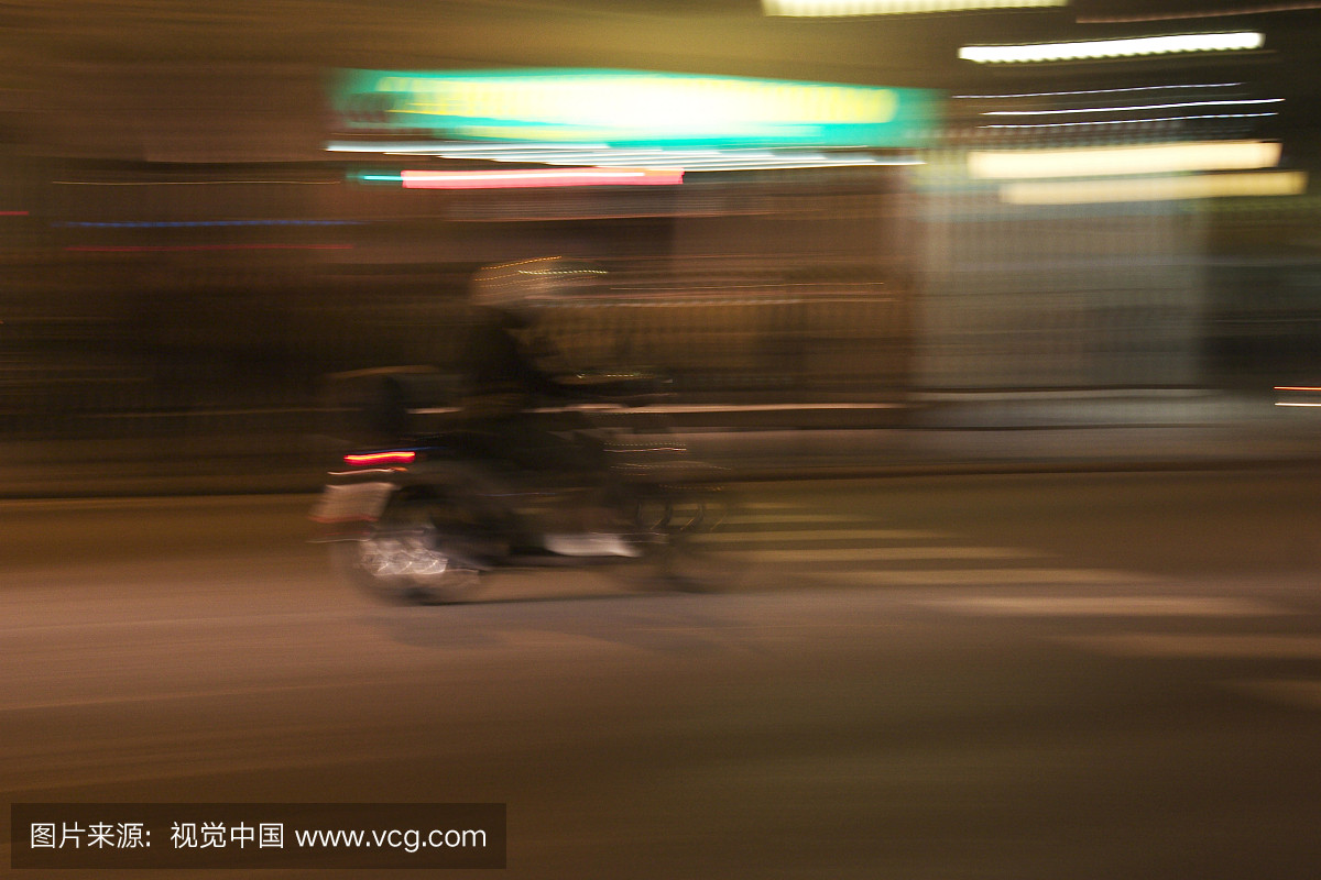 在巴塞罗那夜晚(西班牙)驾驶一辆摩托车的白色