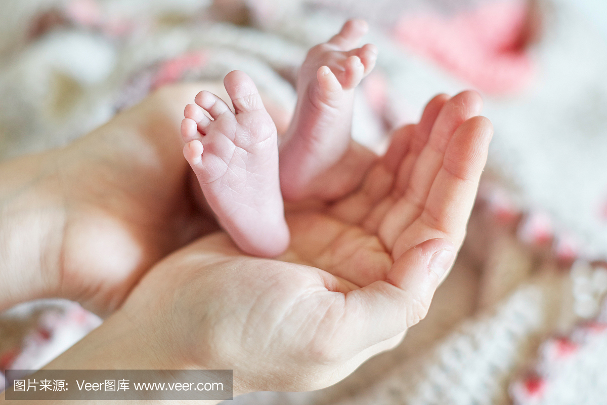 母亲抱着刚出生的婴儿脚在她的手中
