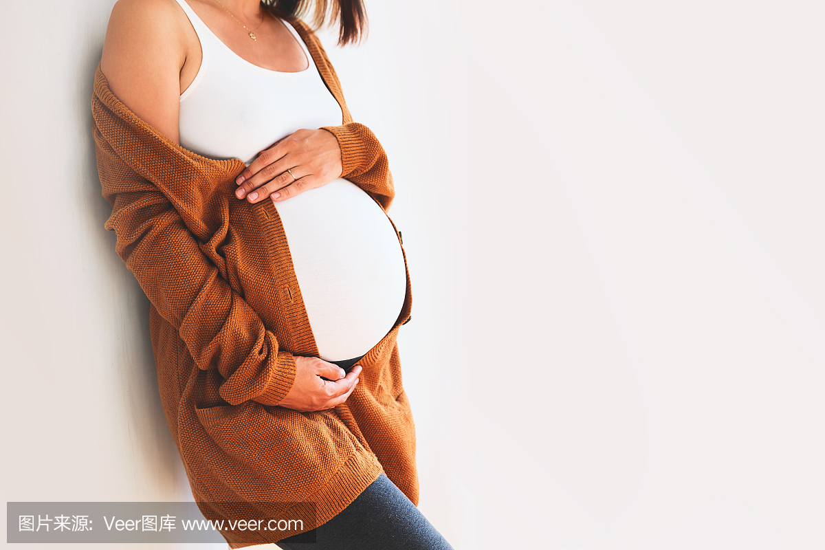 美丽的孕妇,摸她的肚子,用手在白色的背景上。