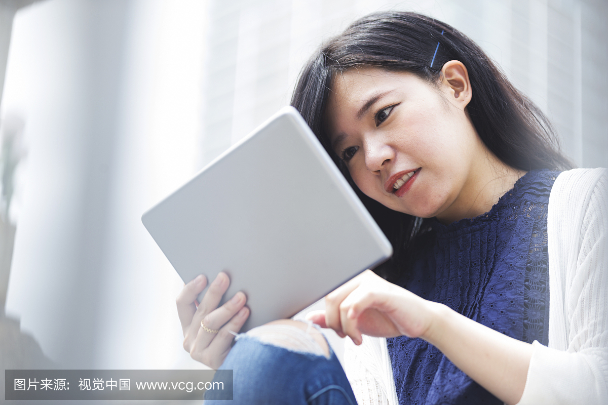 年轻的日本女人密切关注数字平板电脑
