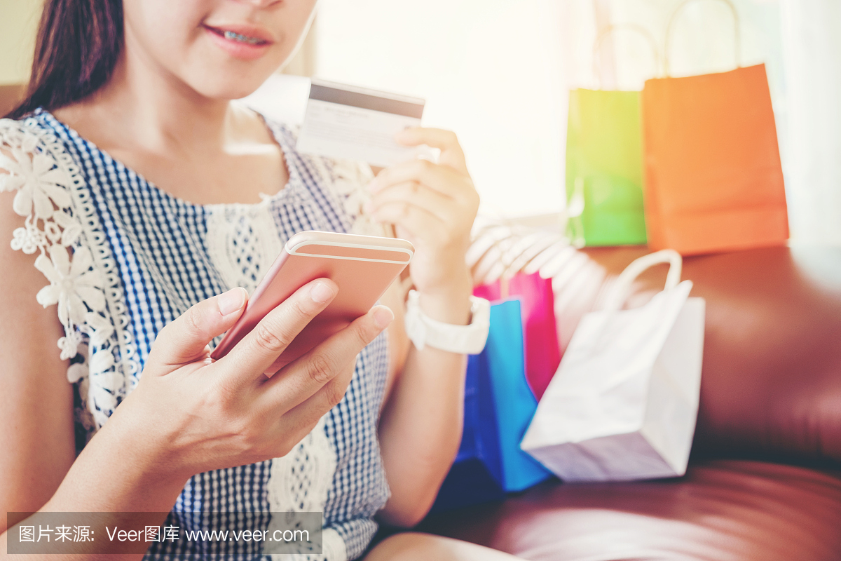 使用智能手机与信用卡在家里享受的女人在线购